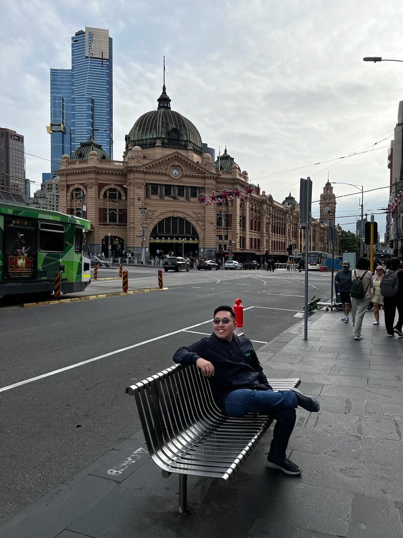 Kenny sitting on a bench near Flinders Street Station in Melbourne