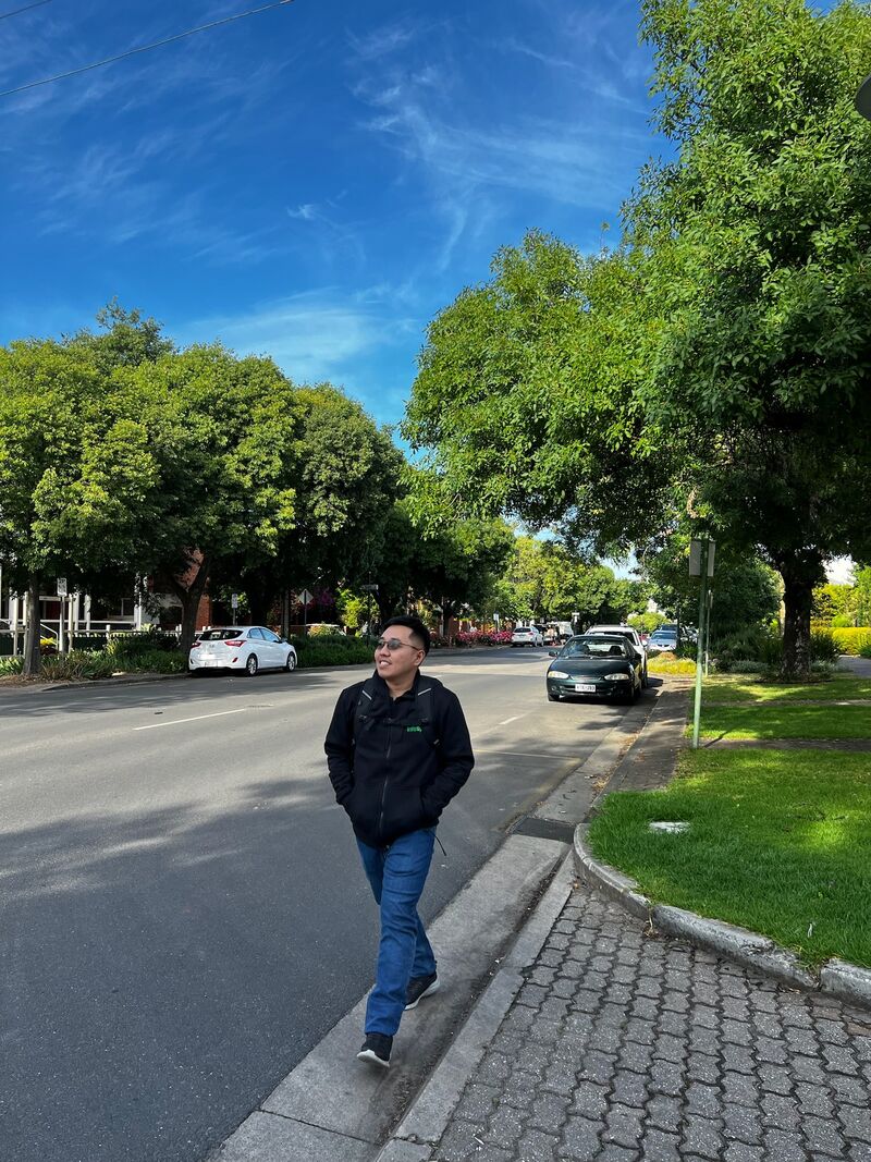 Kenny walking along a tree-lined street in Australia